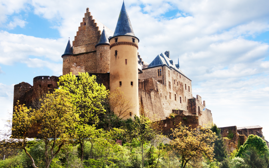 A castle with turrets surrounded by trees on a hill