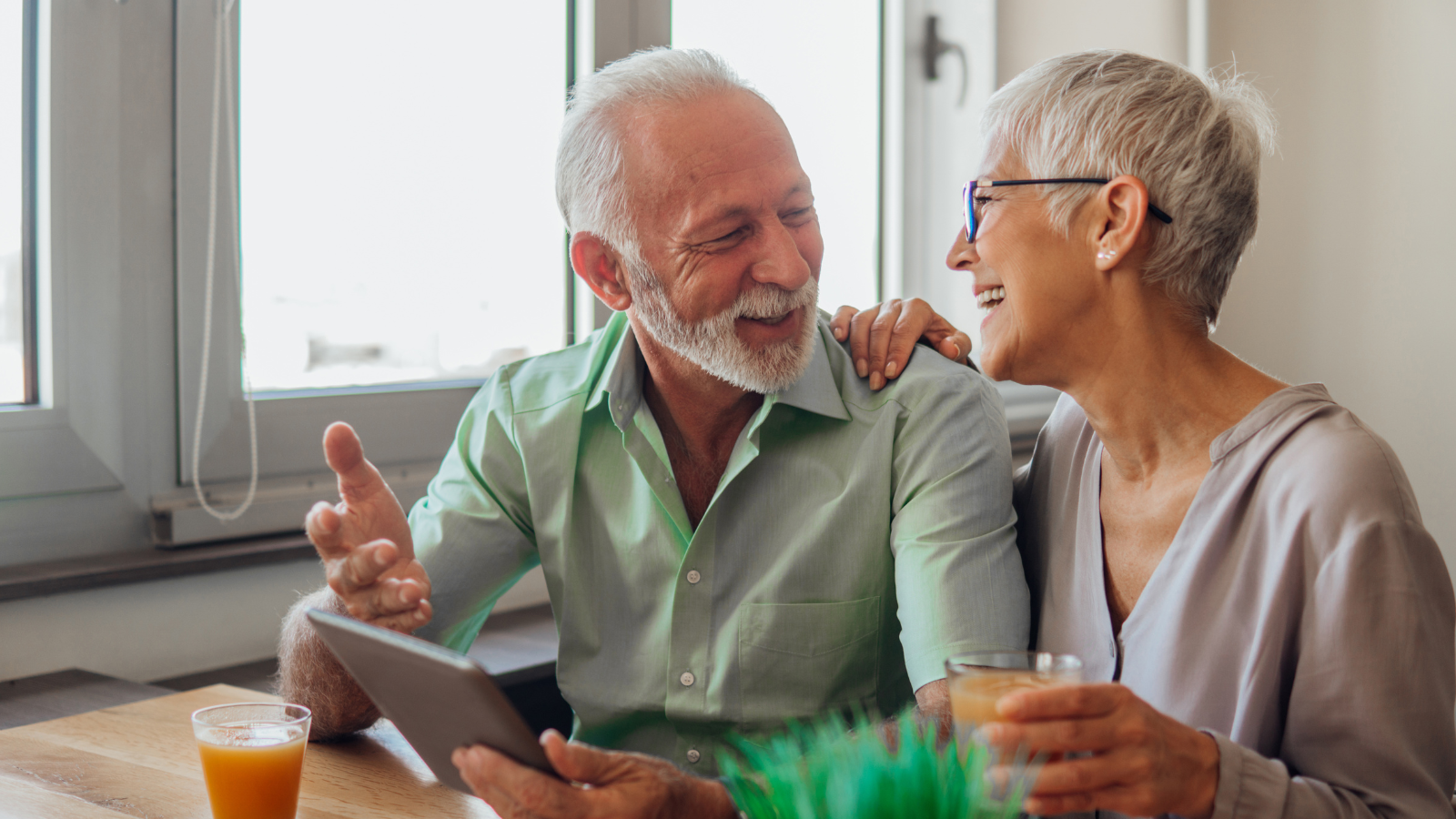 A middle-aged couple chat while using a digital device